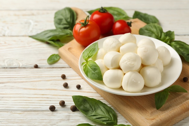 Concepto de comida sabrosa con tazón de queso mozzarella sobre fondo blanco de madera