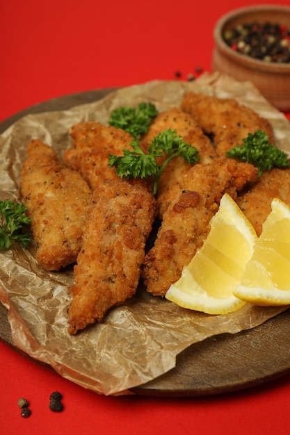 Concepto de comida sabrosa con tiras de pollo sobre fondo rojo.