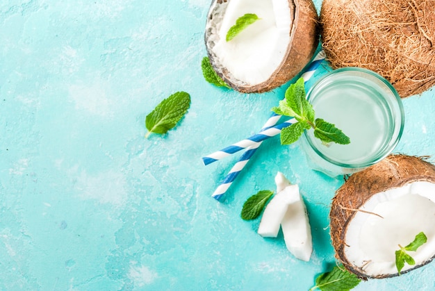 Concepto de comida saludable. agua de coco orgánico fresco con cubitos de hielo de coco y menta sobre fondo azul claro vista superior