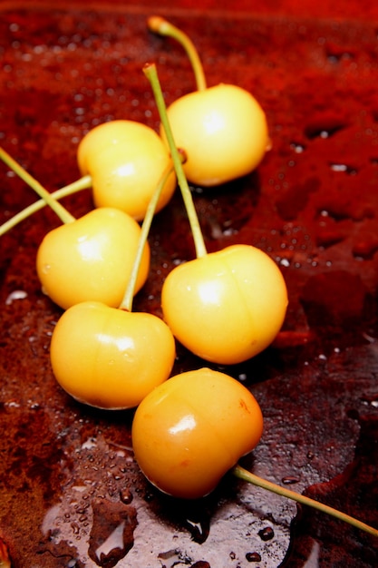 Concepto de comida saludable Cereza amarilla con gotas de agua sobre un fondo negro Vista desde arriba Primer plano de bayas dulces