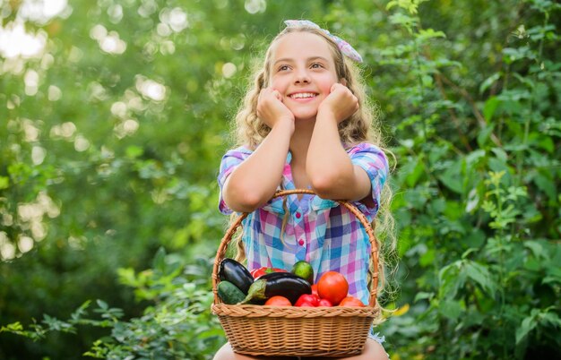 Concepto de comida saludable Chica lindo niño sonriente viviendo una vida saludable Estilo de vida saludable Niño sostenga la cesta con verduras fondo de naturaleza Agricultura ecológica Coma sano Concepto de cosecha de verano Libre de transgénicos