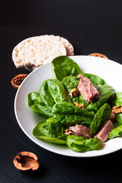 Concepto de comida saludable Ensalada de espinacas con Presskopf francés en plato de cerámica blanca sobre tablero de piedra pizarra negra con espacio de copia