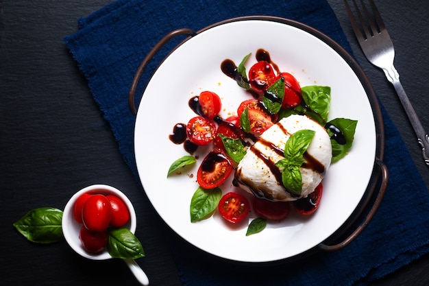 Concepto de comida sana Ensalada Caprese rústica sobre fondo negro con espacio de copia