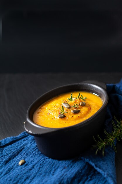 Concepto de comida sana mezcla caliente de sopa de verduras y semillas de calabaza en taza de cerámica negra