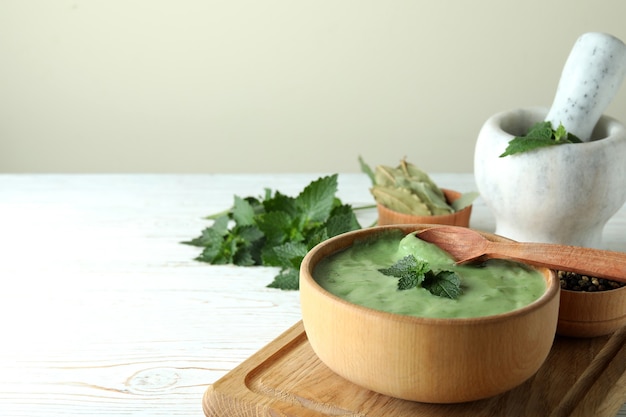 Concepto de comida sana con sopa de ortiga en la mesa de madera blanca