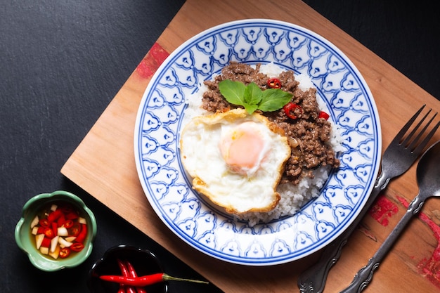 Concepto de comida tailandesa Khao pad krapow arroz y ternera picada Salteado de albahaca sagrada tailandesa con huevo frito en plato de cerámica de estilo tailandés con espacio para copiar