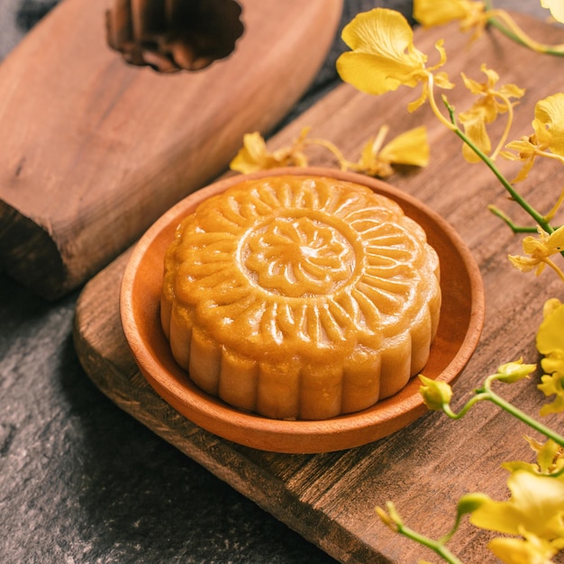 Concepto de comida tradicional del Festival de Medio Otoño Hermoso pastel de luna en la mesa de pizarra negra con flor de molde de pastelería de té cerca del espacio de copia