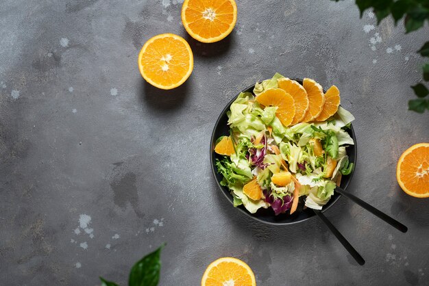 Concepto de comida vegana con ensalada verde y naranjas, vista de arriba hacia abajo con espacio de copia