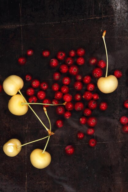 Concepto de comida vegetariana Grosellas rojas jugosas dulces y cerezas amarillas sobre un fondo oscuro Vista desde arriba