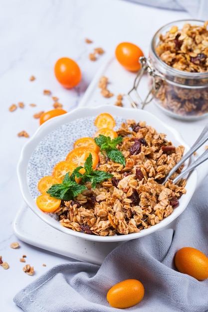 Concepto de comida vegetariana orgánica saludable para comer y hacer dieta. Tazón de budín de chía vegano con granola casera fresca, kumquat de naranja y menta verde para el desayuno