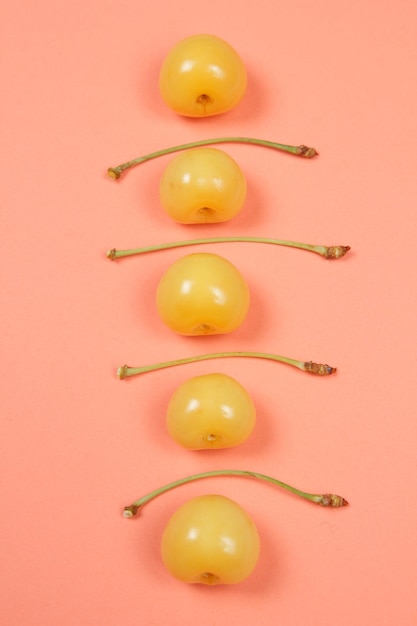 Concepto de comida vegetariana Primer plano Dulces cerezas amarillas jugosas sobre un fondo rosa Vista desde arriba