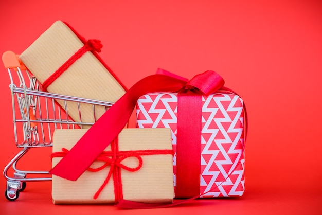 Concepto de compra en línea. Carro de compras y caja de regalo sobre fondo rojo