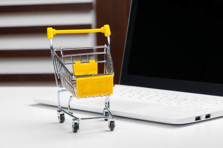 Foto concepto de compra en línea. carro de compras, laptop en el escritorio