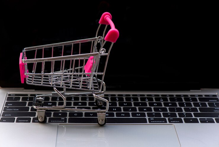 Foto concepto de compra en línea. laptop con mini trolley de mercado