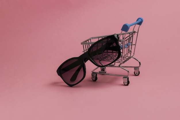 Concepto de compra minimalista Mini carrito de la compra con gafas de sol