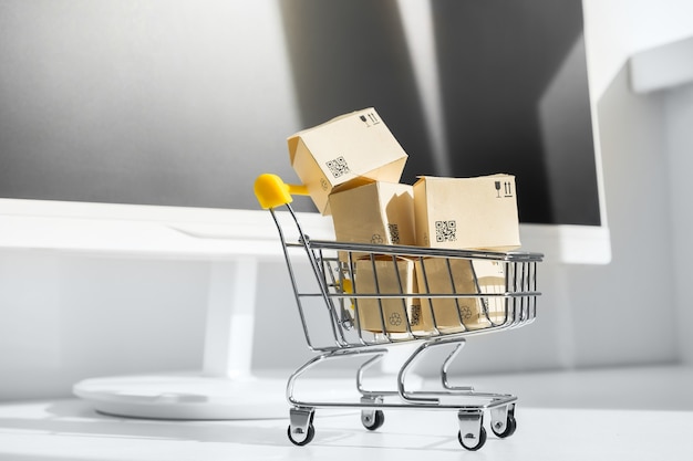 Concepto de compra online. Carrito de compras pequeño con muchas cajas de papel.