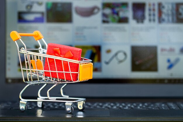 Concepto de compra online. Carro de compras, cajas pequeñas, laptop en el escritorio.