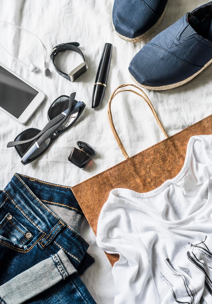 Foto concepto de compra de ropa de mujer jeans zapatillas perfume rímel teléfono gafas de sol bolsa de papel