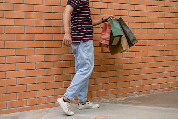 Concepto de compras El chico con sus coloridas bolsas de compras caminando por la calle