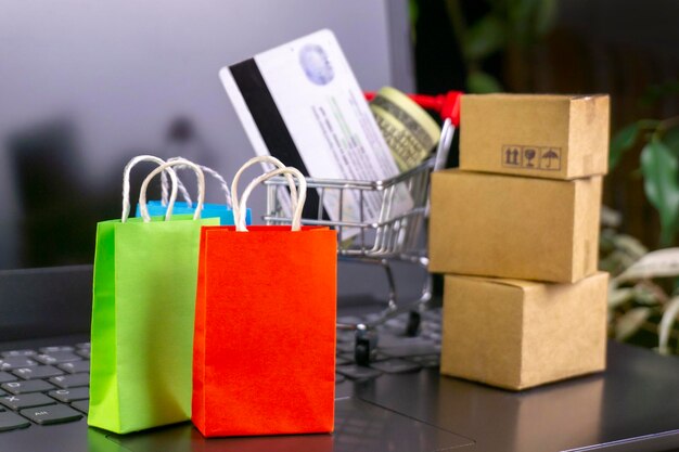 Concepto de compras en línea Cajas de entrega pequeñas Bolsas de compras para teléfonos inteligentes Soporte de cesta de compras en la computadora portátil