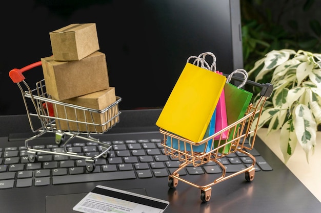 Concepto de compras en línea cajas de entrega pequeñas bolsas de compras para teléfonos inteligentes soporte de cesta de compras en el espacio de copia de la computadora portátil