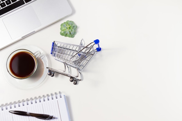 Concepto de compras en línea, carrito de compras con teclado portátil y espacio para copiar café en una mesa blanca