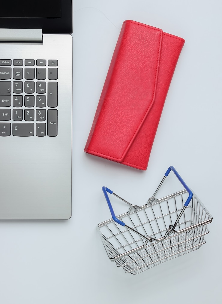 Foto concepto de compras en línea cartera portátil y mini cesta de la compra sobre fondo blanco