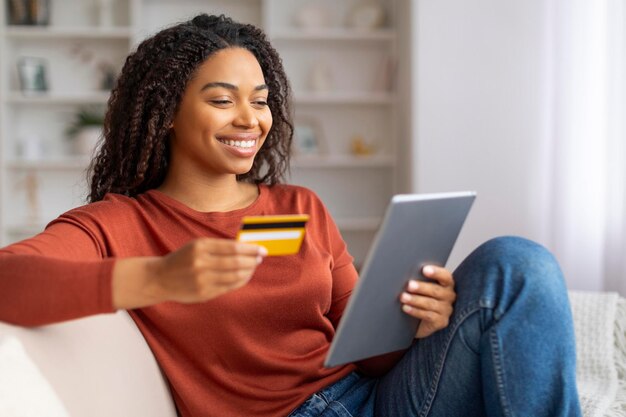 Concepto de compras en línea mujer negra sonriente usando tableta digital y tarjeta de crédito