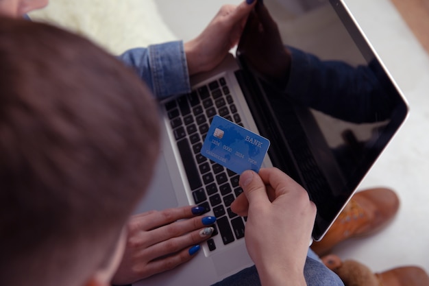 Foto concepto de compras en línea de pareja. tarjeta de crédito en la mano. usando la computadora.