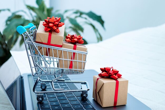 El concepto de compras en línea portátil y pequeño carrito de compras regalos de ventas de Navidad al pedir