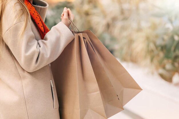 El concepto de compras de mujeres Manos femeninas con bolsas de compras imagen recortada con una bufanda sobre los hombros