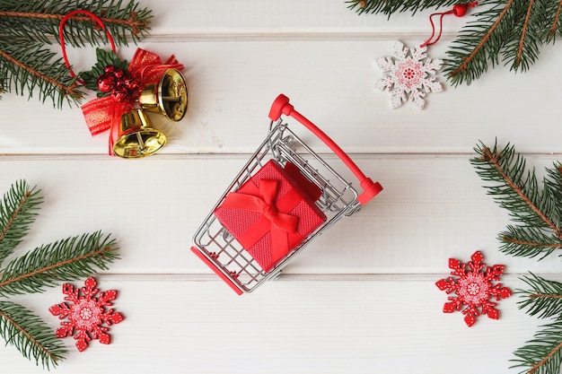 Concepto de compras navideñas Carro de supermercado con regalo sobre fondo de madera festiva Vacaciones de invierno