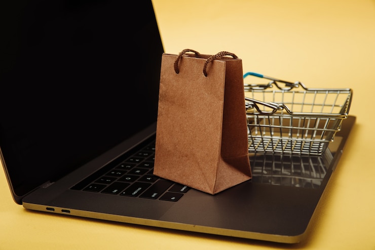 Foto concepto de compras online. bolsa de papel y carro en el teclado del portátil.