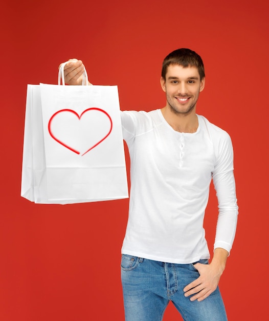 concepto de compras y relaciones - hombre guapo con bolsas de compras y corazón en él