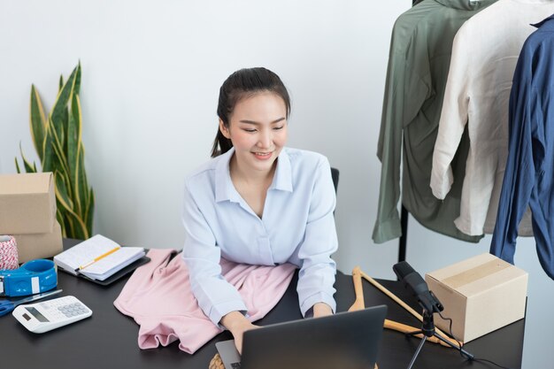 Concepto de compras en vivo una mujer comerciante que responde a los mensajes de los clientes explicando información y promociones de los productos.