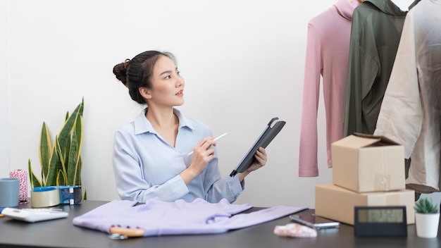 Concepto de compras en vivo una mujer comerciante que usa un lápiz de tableta deslizando la tableta para verificar los pedidos del día.