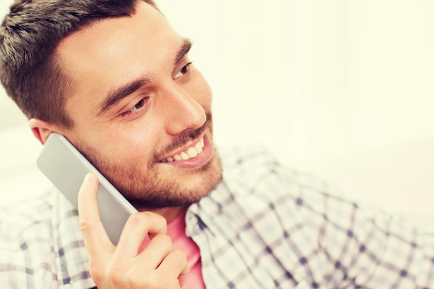 concepto de comunicación, tecnología y personas - joven sonriente llamando a un teléfono inteligente