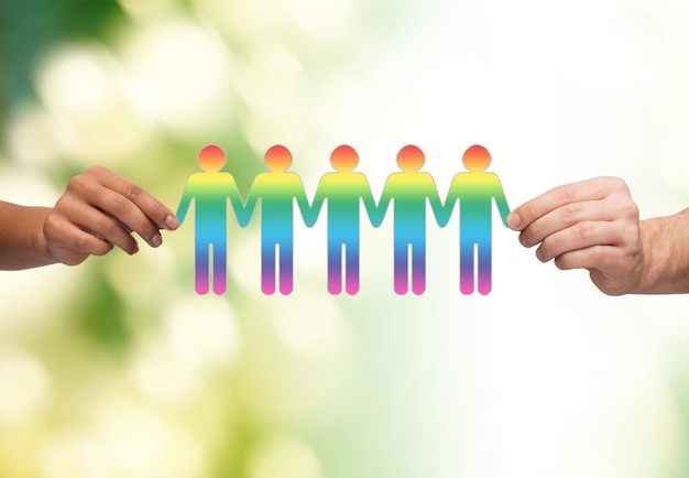 concepto de comunidad, unidad y trabajo en equipo - cierre de manos de parejas multirraciales sosteniendo una cadena de papel gente gay recortada sobre fondo verde