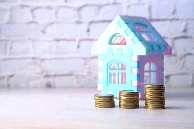 El concepto de concepto de finanzas con pila de monedas y casa en la mesa.