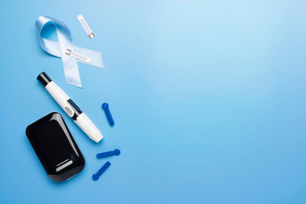 Concepto de concienciación sobre la diabetes de tiras de prueba de medidor de glucosa de cinta y lancetas sobre fondo azul