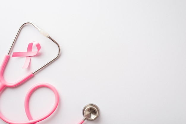 Concepto de concientización sobre el cáncer de mama Foto de vista superior de cinta de seda rosa y estetoscopio sobre fondo blanco aislado con espacio de copia