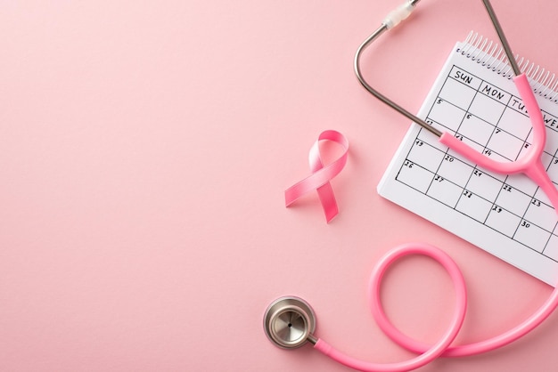 Concepto de concientización sobre el cáncer de mama Foto de vista superior del estetoscopio de cinta de seda rosa y calendario sobre fondo rosa pastel aislado con espacio de copia