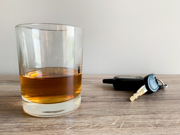 Concepto de conducir ebrio. Vaso con whisky y llave en la mesa.