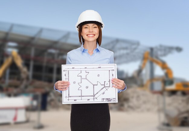 concepto de construcción, desarrollo, construcción y arquitectura - mujer de negocios sonriente con casco blanco que muestra planos