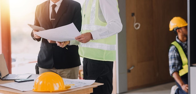 Concepto de construcción y estructura de una reunión de ingenieros o arquitectos para un proyecto que trabaja con socios y herramientas de ingeniería en la construcción de modelos y planos en el contrato de obra para ambas empresas