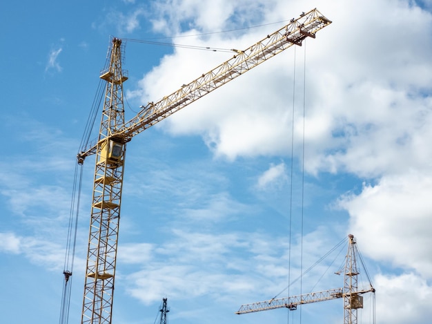 Concepto de construcción. Grúas torre contra un cielo azul brillante con nubes. Foto horizontal.