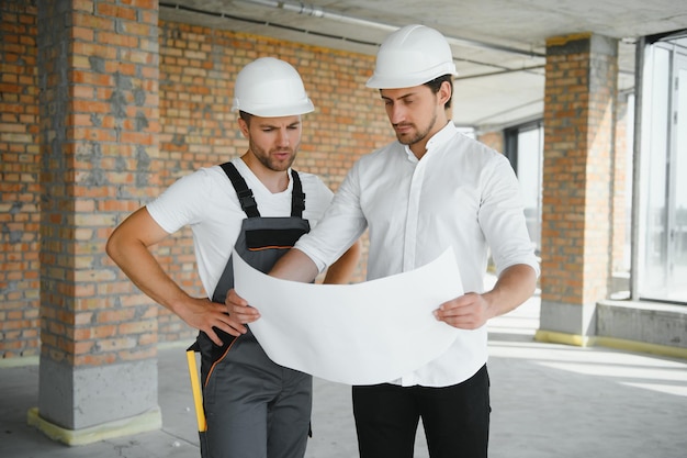 Concepto de construcción de Ingeniero y arquitecto trabajando en el sitio de construcción con impresión azul