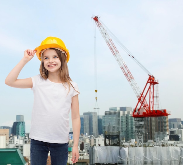 concepto de construcción y personas - niña sonriente con casco protector mirando hacia arriba