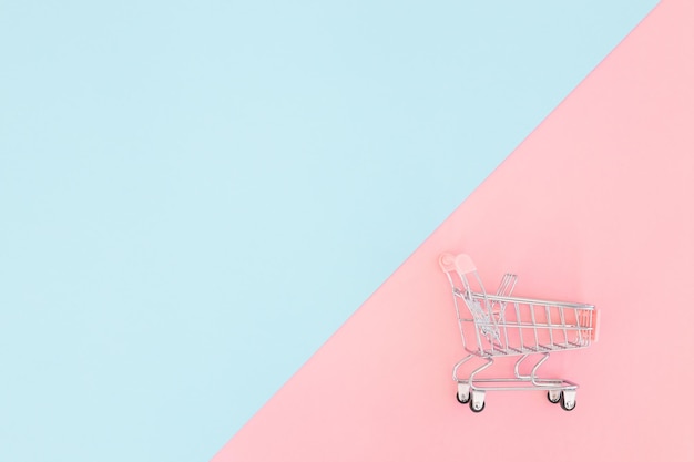 Concepto de consumidor mini carrito de compras para comprar en una vista superior de minimalismo de fondo de color