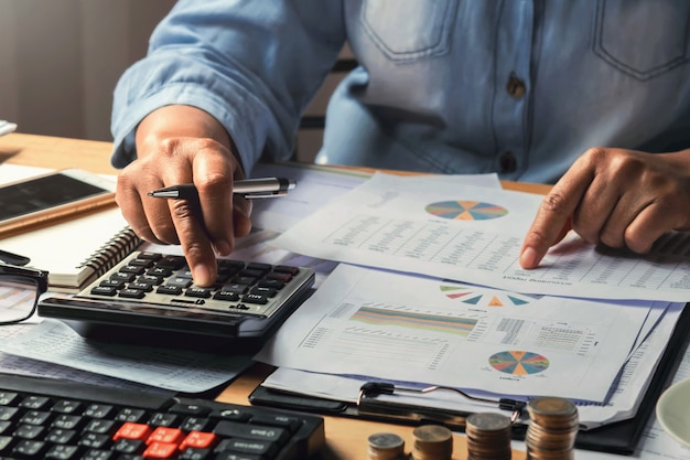 Foto concepto de contabilidad. empresaria trabajando con calculadora con pila de dinero en la oficina
